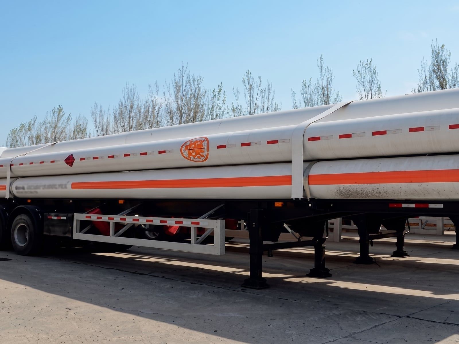 Semi-remorque de transport de GNC, faisceau de bouteilles vu de côté, marquages de danger visibles le long des tubes