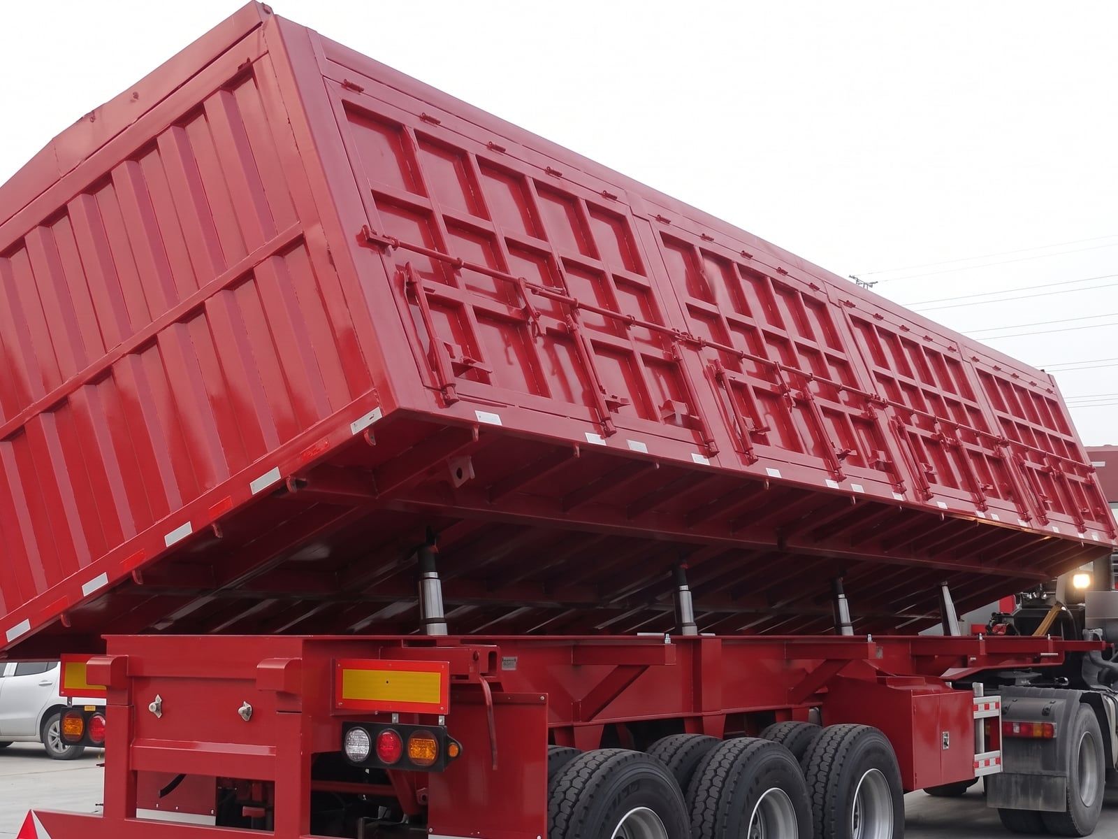 Semi-remorque CYP9400L 60 à basculement latéral, caisse rouge vue de trois quarts arrière, basculée