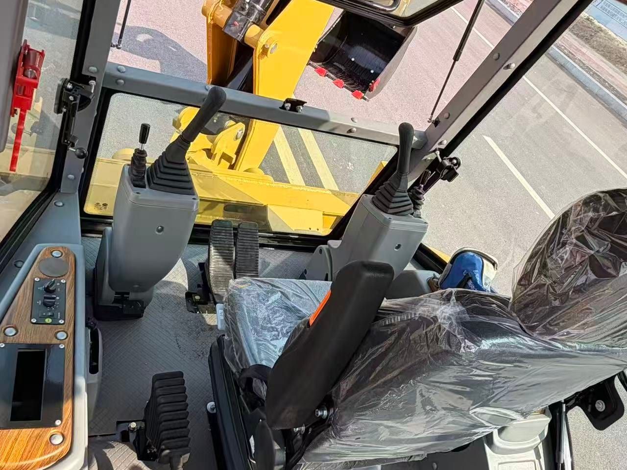 LJ3CX-A backhoe loader cab interior: the operator seat still wrapped in plastic, the control levers and the side console