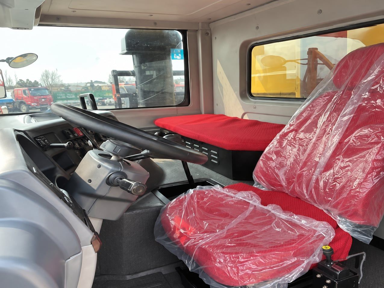 Camion minier à caisse large SDLG, intérieur de la cabine : volant à gauche, siège encore sous le plastique de livraison