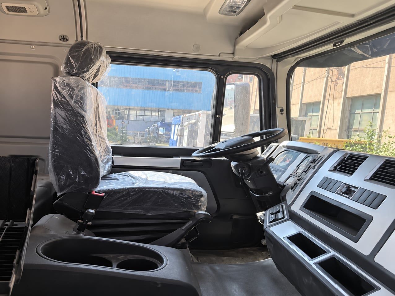 Camion citerne d'eau Shacman Delong F3000 6×4, intérieur de la cabine : volant à gauche, tableau de bord et sièges encore sous le plastique de livraison