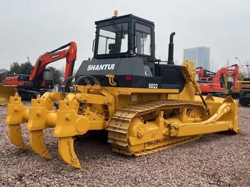 Shantui SD22 bulldozer from the rear, the three-shank ripper and the cab, excavators behind