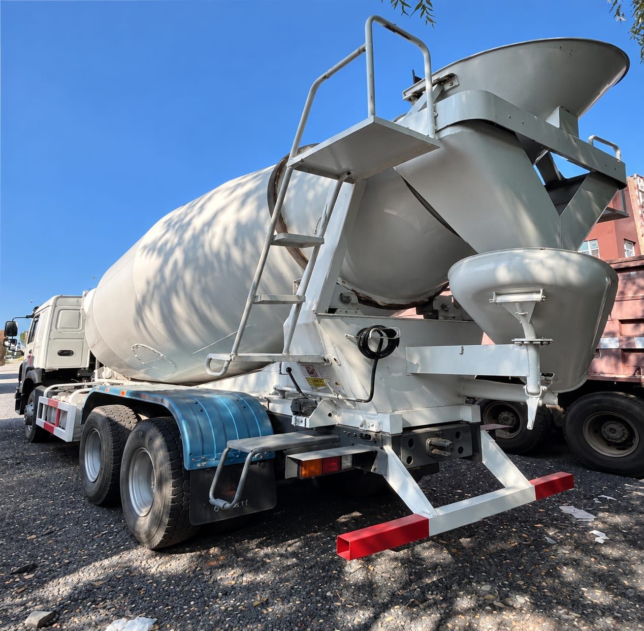 Camion malaxeur Sinotruk HOWO 6×4, vue arrière, cuve, goulotte de déchargement et trémie de chargement visibles