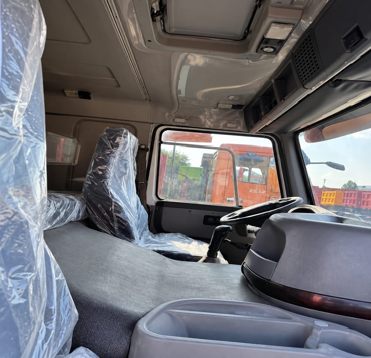 Camion malaxeur Sinotruk HOWO 6×4, intérieur de la cabine : volant à gauche et sièges encore sous leur emballage d'usine