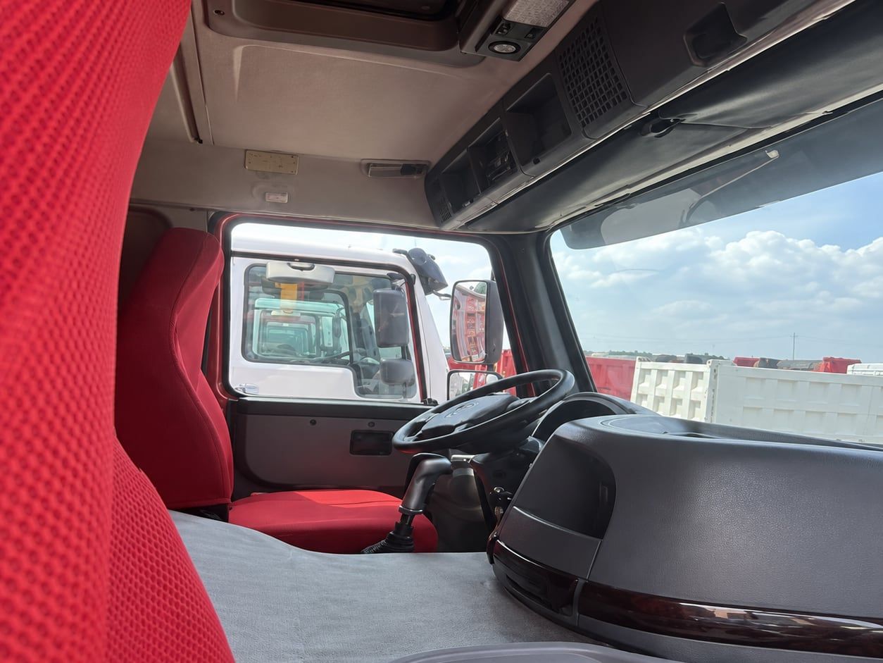 Camion benne Sinotruk HOWO 6×4, intérieur de la cabine : volant à gauche, volant, tableau de bord et sellerie rouge