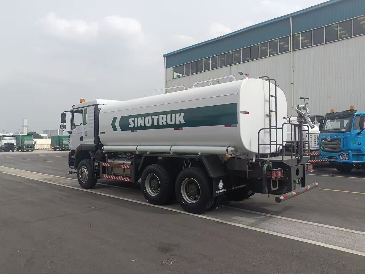 Camion citerne d'eau Sinotruk HOWO 6×4, vue de trois quarts arrière, citerne blanche avec bande Sinotruk, échelle arrière, garde-corps de passerelle et rampe d'arrosage