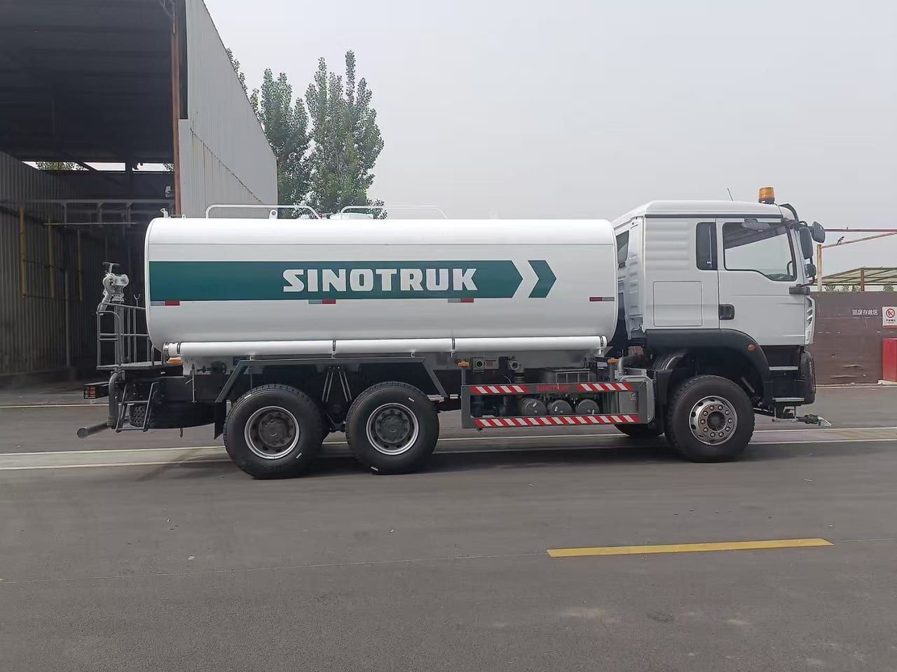 Camion citerne d'eau Sinotruk HOWO 6×4, vue de profil, citerne sur châssis à trois essieux et coffres de pompe sous la citerne