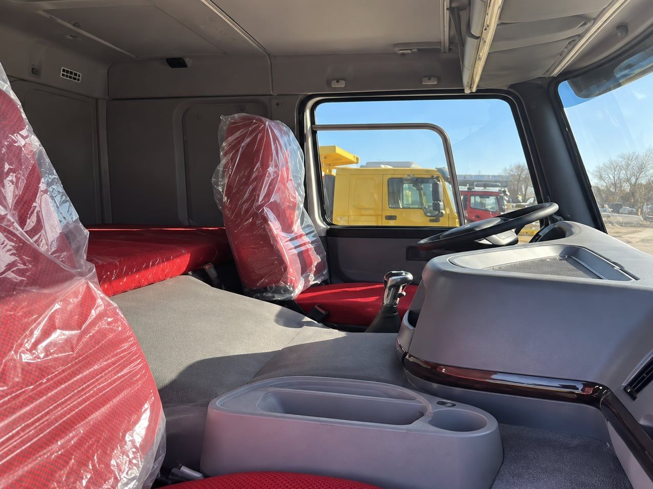 Camion benne Sinotruk HOWO 8×4, intérieur de la cabine, sièges encore sous le plastique de livraison