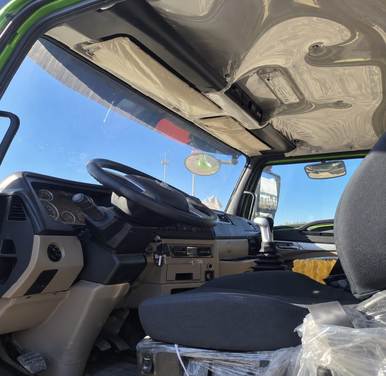 Camion benne Sinotruk HOWO 8×4, intérieur de la cabine : volant, combiné d'instruments et levier de vitesses