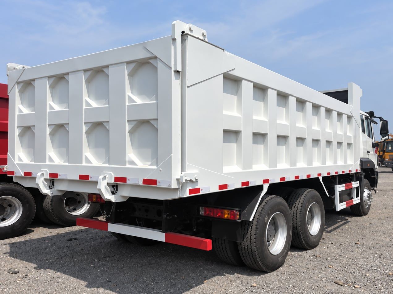 Camion benne Sinotruk HOWO NX 6×4, benne blanche vue de trois quarts arrière, deux essieux arrière visibles