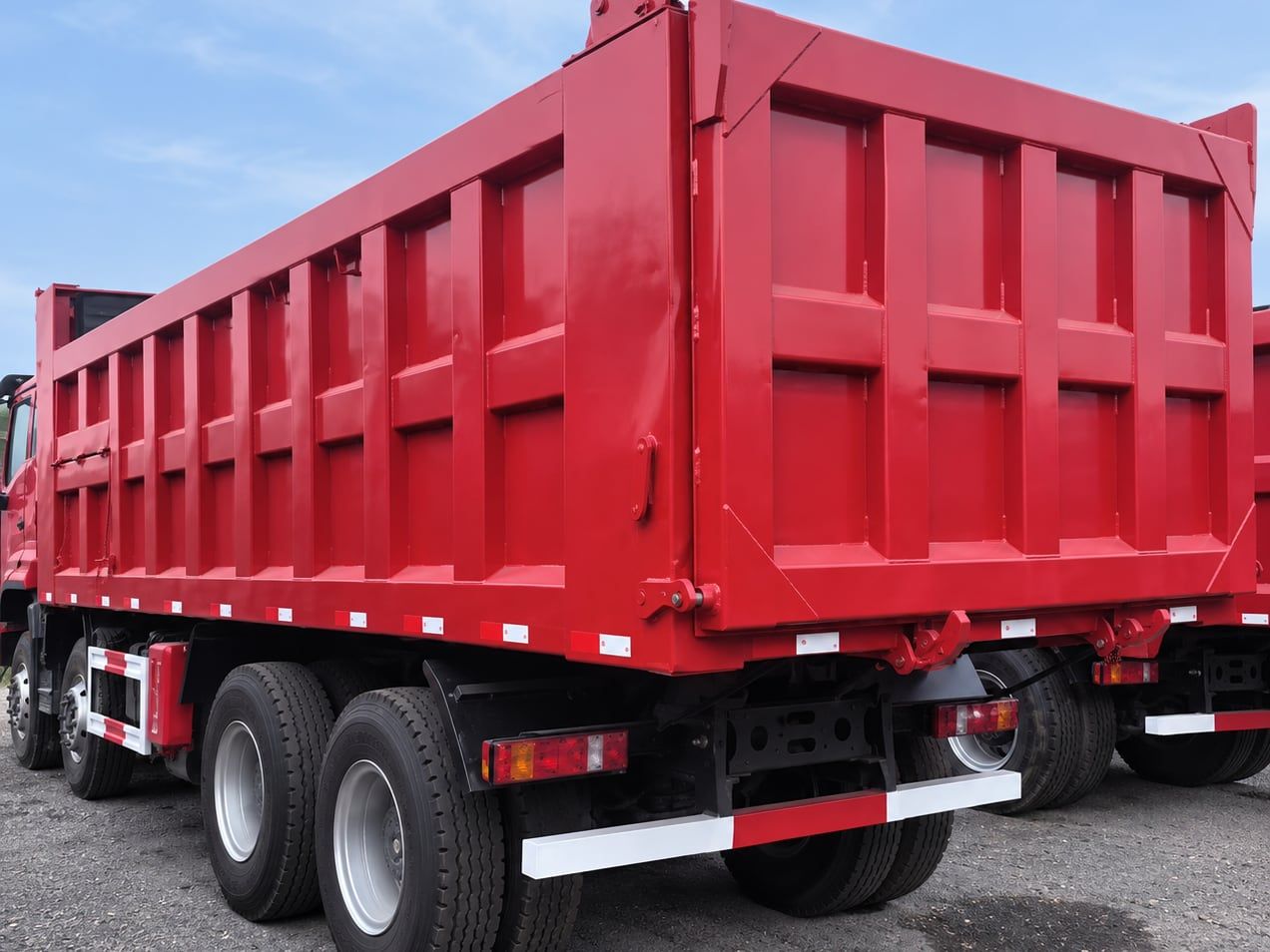 Camion benne Sinotruk HOWO NX 8×4, benne rouge vue de l'arrière, porte arrière fermée