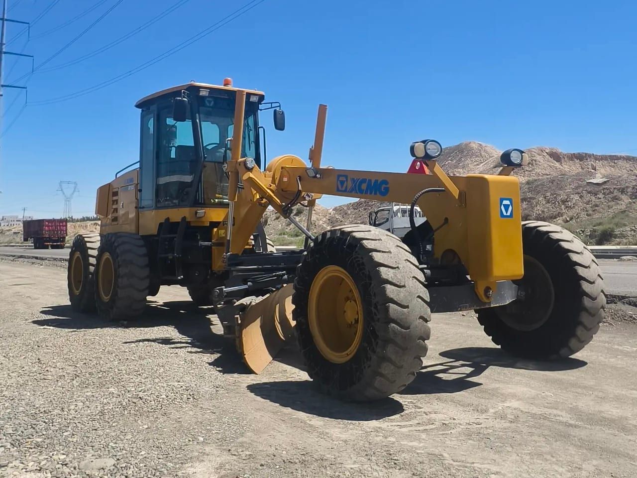 XCMG GR1803 motor grader from the front on gravel, front wheels, the long frame and the cab behind