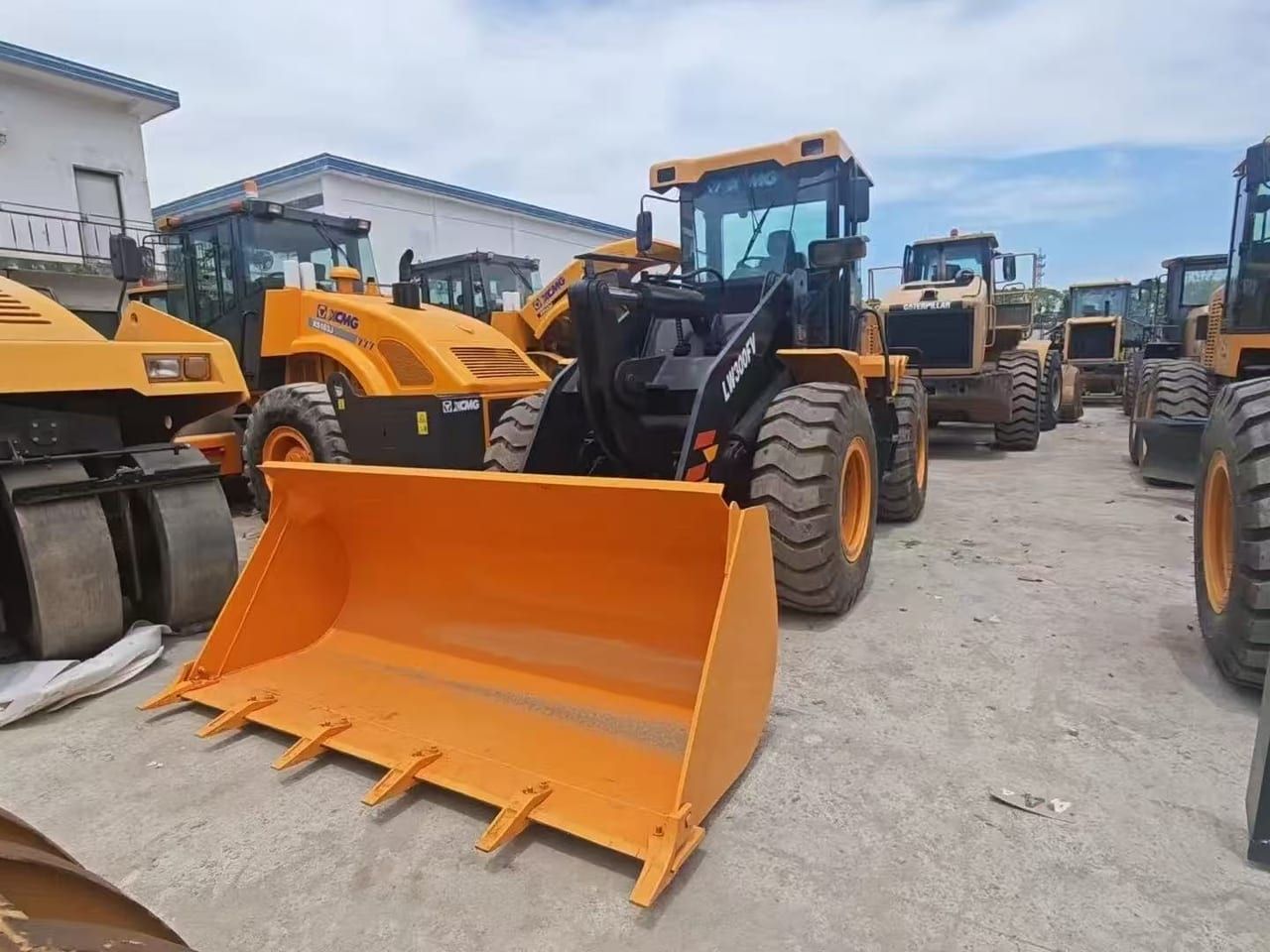 XCMG LW300FV wheel loader from the front, the orange bucket lowered flat, in a yard of loaders