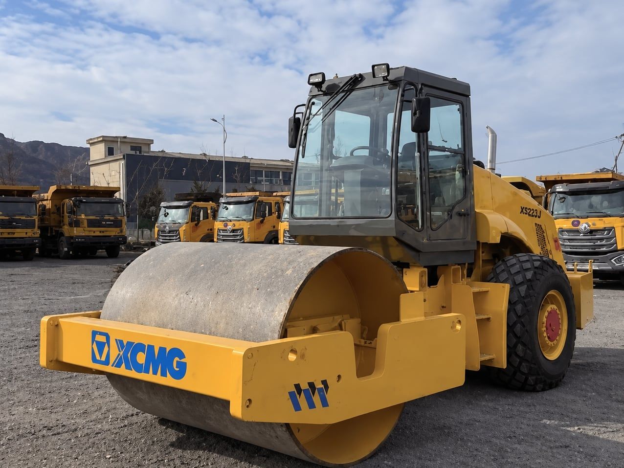 Compacteur monocylindre XCMG de 22 t, vue de trois quarts avant, cylindre et cabine de l'opérateur, machines en arrière-plan dans le parc